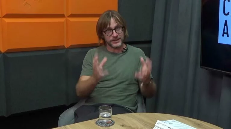 Daniel Petryczkiewicz gestykuluje podczas rozmowy w studiu Cafe Akcja