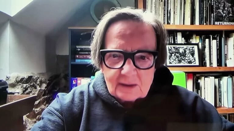Agnieszka Holland w okularach połączona zdalnie na tle regałów z książkami, Cafe Akcja