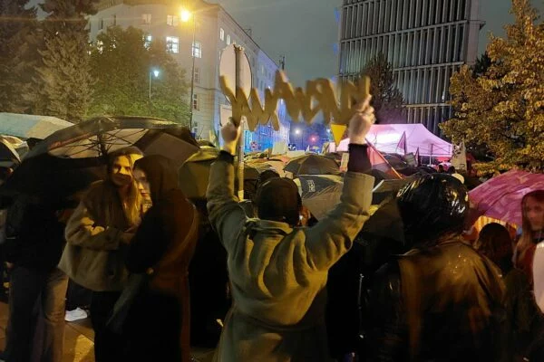 Uczestniczki protestu z uniesionym napisem pod Sejmem w deszczu