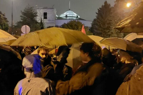 Protestujące osoby pod parasolami, w tle Sejm